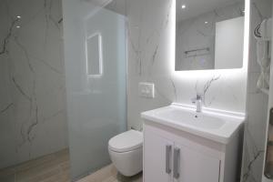 a white bathroom with a toilet and a sink at Moonshine Hotel in Ksamil +83 photos
