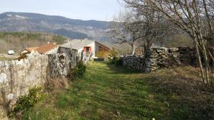 Ein Steinzaun und ein Haus auf einem Feld in der Unterkunft Gîte BARD des OURS in Saint-Martin-en-Vercors