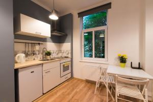 een keuken met witte kasten en een tafel en stoelen bij Light Studio Apartment in Liepāja