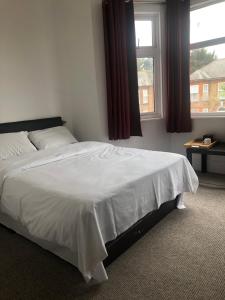 a bedroom with a large white bed with a window at Saji Hotel Illford in Ilford