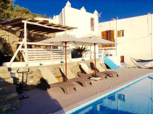a deck with chairs and an umbrella next to a pool at Seatinview Lodges in Mikonos