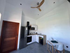 a kitchen with a refrigerator and a table and a ceiling fan at L'Eté sans fin, vue mer in Filaos +2 photos