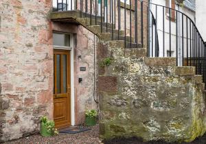 a stone building with a wooden door and a staircase at The Hideaway in Inverness