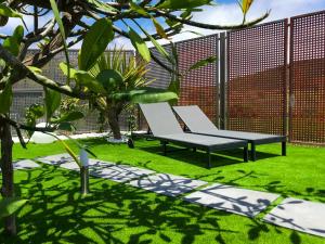 a bench sitting on the grass next to a fence at Villa Loft Jacuzzi Teleworking WIFI in San Miguel de Abona