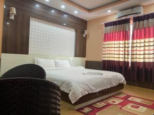 a bedroom with a bed and a chair and a window at Hotel Gorkha Palace Pvt. Ltd in Gorkhā