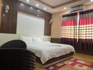 a bedroom with a bed and a window and a chair at Hotel Gorkha Palace Pvt. Ltd in Gorkhā