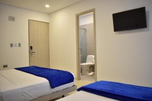 a bedroom with two beds and a bathroom with a toilet at Hotel Blu Cúcuta in Cúcuta