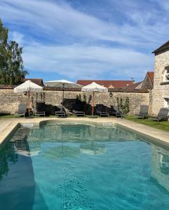 una piscina con acqua blu di fronte a un edificio di La Closerie de Gigny Maison Templiere avec Piscine,jacuzzi a Gigny