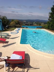 een zwembad met stoelen en mensen in het water bij Le gîte du mas avec piscine in Bourganeuf