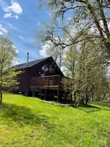 ein großes Holzhaus mit einer Terrasse auf einem Feld in der Unterkunft Fern Lodge in Dalavich