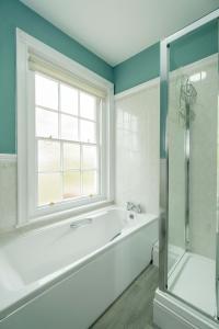 a bathroom with a bath tub and a window at 4 Crespigny House - Aldeburgh Coastal Cottages in Aldeburgh +23 photos