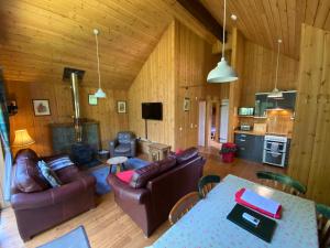 a living room with couches and a table and a kitchen at Fern Lodge in Dallavich