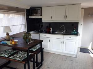uma cozinha com armários brancos e uma mesa de madeira em Chalet Campingpark Capfun De Bongerd 5-star em Tuitjenhorn