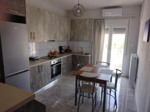 "Thea" Valis Apartments في Melissátika: مطبخ مع طاولة وكراسي وثلاجة