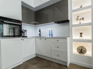 uma cozinha com armários brancos e electrodomésticos pretos em Aquarius Residence apartament 203 em Boszkowo