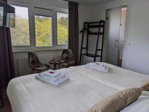 1 Schlafzimmer mit 2 Betten, 2 Stühlen und Fenstern in der Unterkunft Bed&Bubbels 256 in De Koog