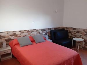 ein Schlafzimmer mit einem roten Bett und einem schwarzen Stuhl in der Unterkunft Vv Puerto del Trigo - Sirena in Alojera