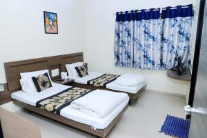1 dormitorio con 2 camas y ventana en Hotel Annapura Residency, Chalisgaon, en Chālisgaon