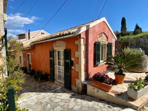 een oranje huis met zwarte luiken op een straat bij Corfu Rural-Chic Gems in Ágios Prokópios
