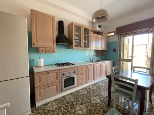 a kitchen with wooden cabinets and a table with a microwave at casa in spiaggia in Marina di Pescoluse