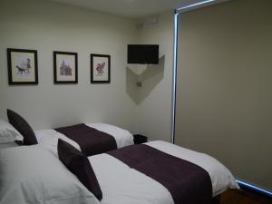 Pokój z dwoma łóżkami i telewizorem na ścianie w obiekcie Liver View Apartments w Liverpoolu