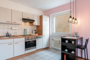 uma cozinha com armários brancos e uma janela em FREE LIVING - Tropical Design Apartments, Zentral, Parkplatz, Küche, Wlan em Wolfsburg