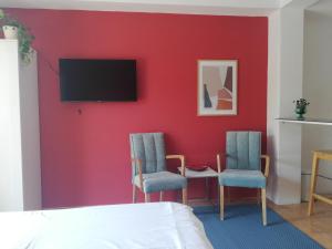 a bedroom with a red wall with two chairs and a tv at Sajeta Beach Apartments in Drvenik