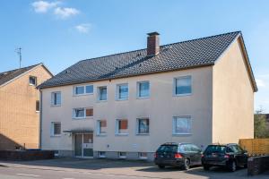two cars parked in front of a large house at Immo-Vision - Modern Living Apartments, Zentral, Parkplatz, Küche, Wlan in Wolfsburg