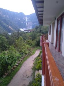 a dirt road next to a fence with a waterfall in the background at La Rivera de Gocta in Cocachimba