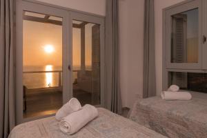 two beds in a room with a view of the ocean at Avgi Villa in Agios Nikolaos +62 photos