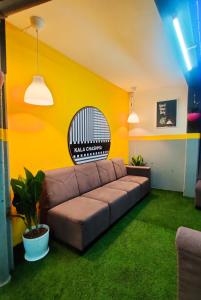 ein Wohnzimmer mit einem braunen Sofa und einer gelben Wand in der Unterkunft Procida Hostel by Zero Jhanjhat in Pune