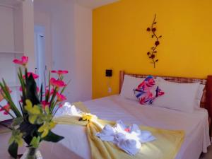 a bedroom with a white bed with a vase of flowers at MarTito Forno Pousada - Armação dos Buzios in Búzios +69 photos