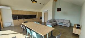 cocina y sala de estar con mesa de madera y sillas en Maison Belle Vue, en Gouvy