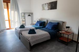twee bedden in een slaapkamer met blauwe kussens erop bij URBAN B. in Bologna