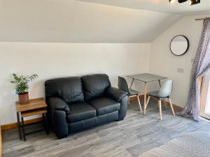 a living room with a black leather couch and a table at Holmview apartment in Stornoway