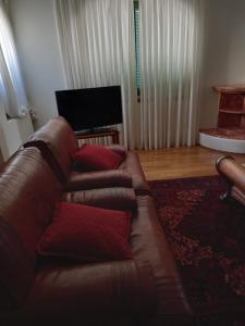 a brown leather couch in a living room with a television at Francelos Village in Vila Nova de Gaia