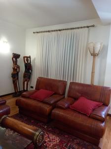 a living room with a brown leather couch and red pillows at Francelos Village in Vila Nova de Gaia