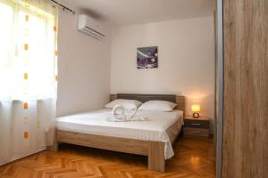 a bedroom with a bed with white sheets and a mirror at Apartment Goli in Komiža