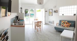 a kitchen and living room with a couch and a table at Appartement neuf clim terrasse & piscine in Blauzac