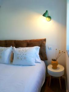 een slaapkamer met een bed met witte kussens en een tafel bij Da' Vila - Alojamento Local in Ponte de Lima