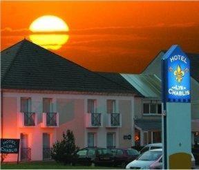 un hotel con un cartel frente a un edificio en Aux Lys de Chablis, en Chablis