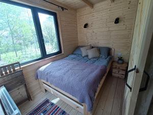 Łóżko w drewnianym pokoju z oknem w obiekcie Zdalnie z Lasu - Siedlisko w Puszczy Białowieskiej w mieście Narewka