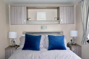 1 dormitorio con 1 cama con almohadas azules en Silver Birch Retreat - Percy Woods Country Retreat With 18 HOLE FREE GOLF, en Alnwick