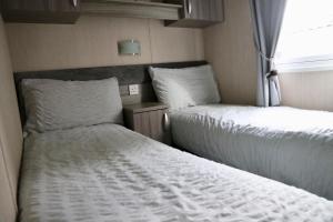 two beds in a small room with a window at Silver Birch Retreat - Percy Woods Country Retreat With 18 HOLE FREE GOLF in Alnwick