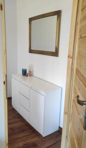 eine weiße Kommode in einem Zimmer mit Spiegel in der Unterkunft Apartament Spokojny in Mielno