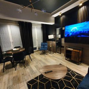un soggiorno con grande TV, tavolo e sedie di Apartamenty Kąpielowa Złoty a Ełk