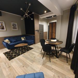 un soggiorno con un divano blu e un tavolo di Apartamenty Kąpielowa Złoty a Ełk