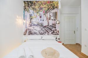 a bedroom with a white bed with a painting of a street at Katy's Home in Naxos Chora