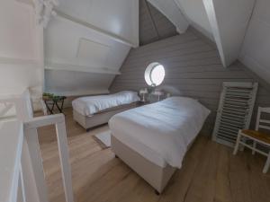 Un dormitorio abuhardillado con dos camas y una ventana. en B&B Hoeve Klein Haneveld, en Sint-Oedenrode