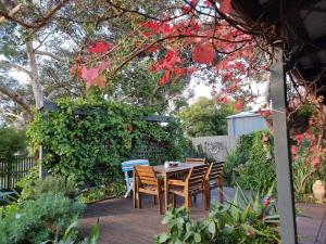 a table and chairs on a deck in a garden at Little Port Cottage in Portarlington